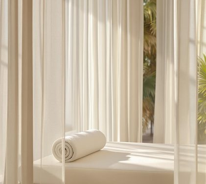 A treatment bed by a sunlit, curtained window.