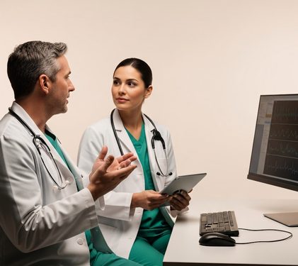 Two doctors talking through notes at a desk.
